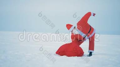 穿着圣诞老人<strong>服装</strong>的人从地上捡起一个装有礼物的<strong>袋子</strong>，特写。